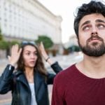 A woman and a man are standing on the street and seem to argue. The woman is looking angry and the man is annoyed.