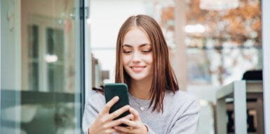 A woman lokking at her phone, thinking about "should I call him?"