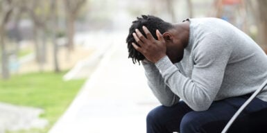 A woman experiencing unrequited love, looking at her phone while sitting at a window.