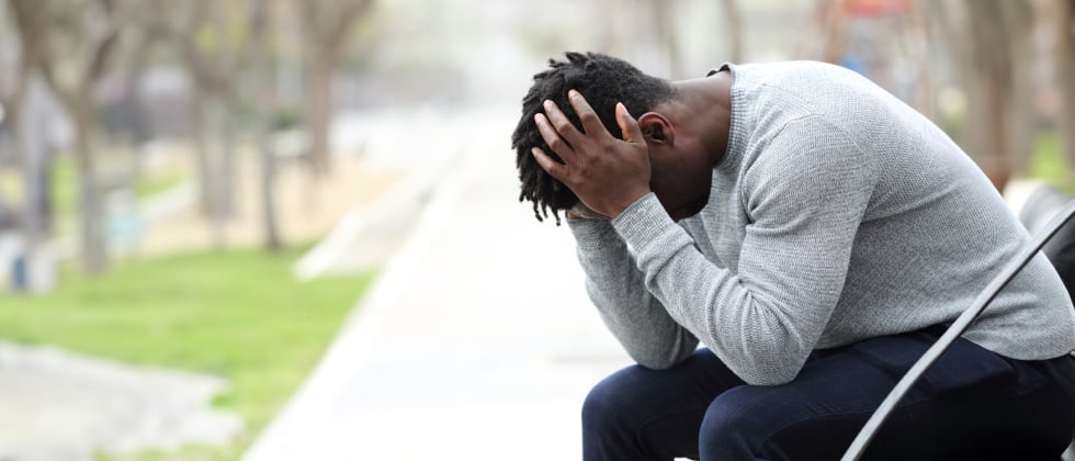 A woman experiencing unrequited love, looking at her phone while sitting at a window.
