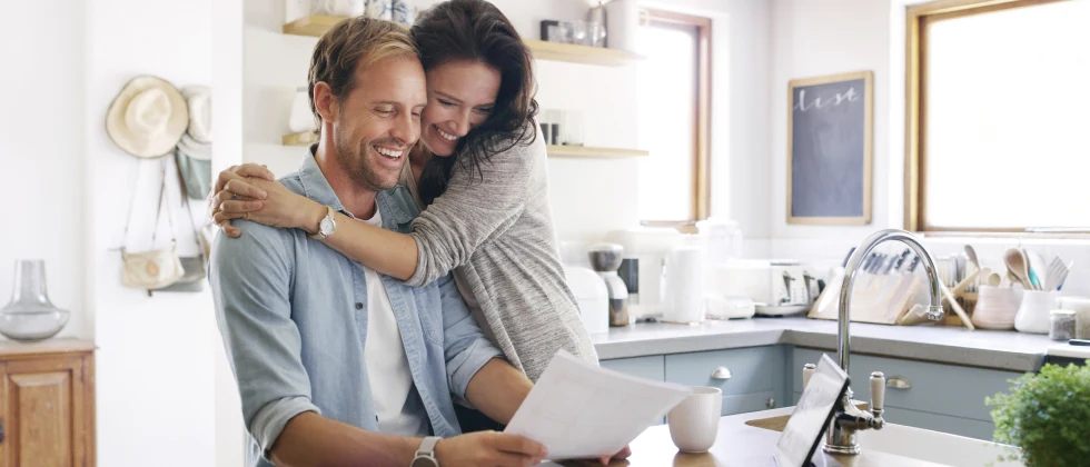 A couple hug each other in the kitchen. 