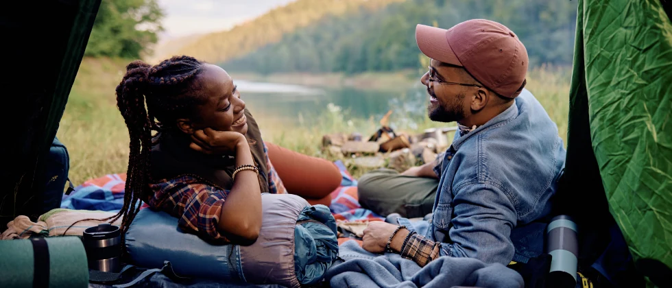 A couple in a tent in nature, talking and eating.