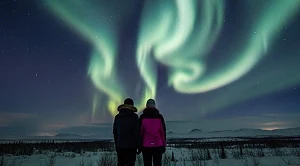 A couple looking at the northern lights at night. 