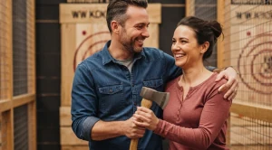 A couple holding an axe, on an axe throwing activity.