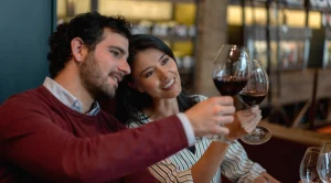 A couple is looking at their glasses of wine at a tasting.