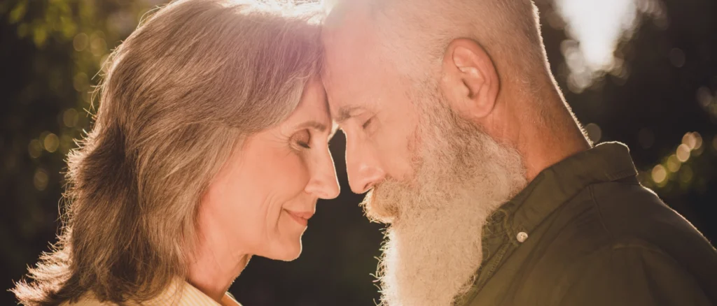Loving senior couple standing forehead to forehead at sunset.