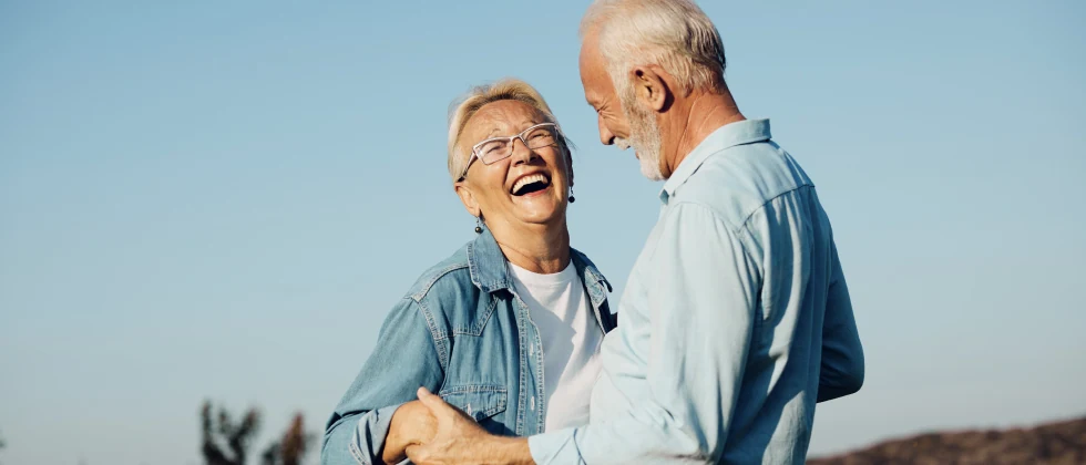 A couple holding hands and smiling at each other in the nature,