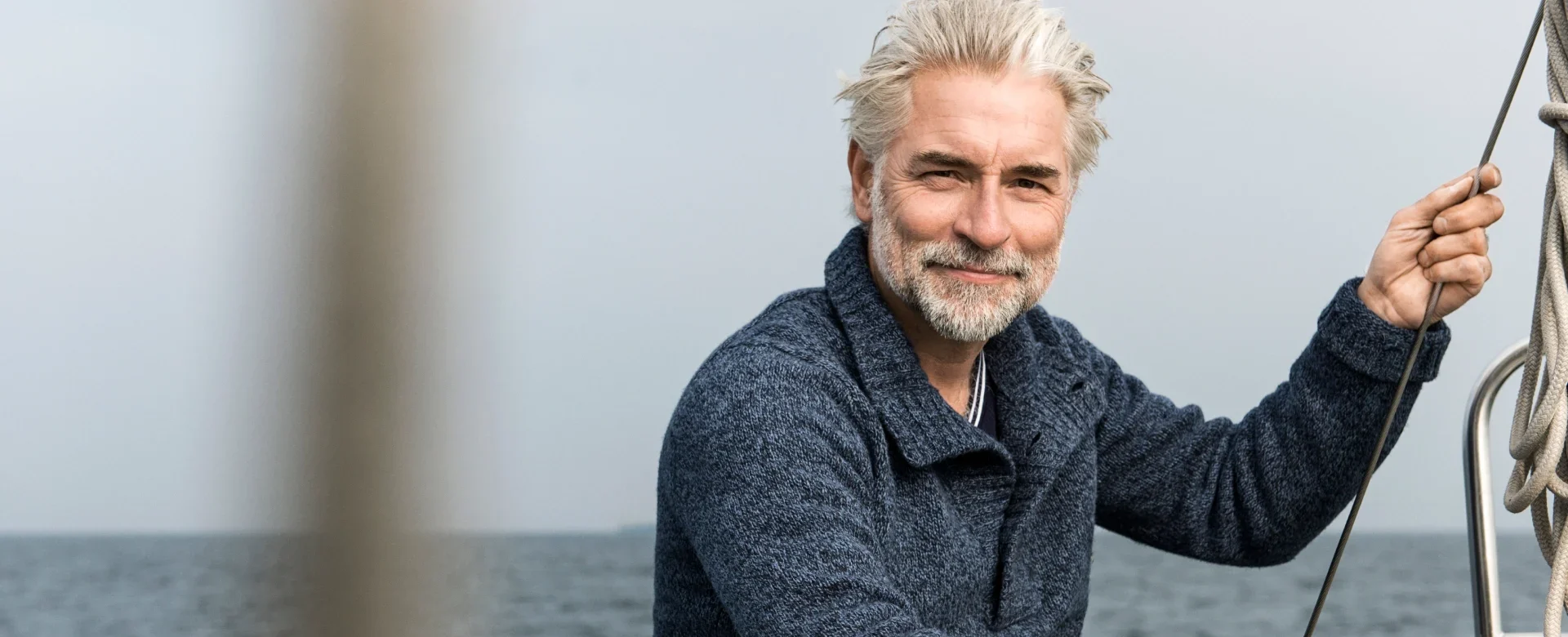 Handsome senior man smiling on a boat by the sea.