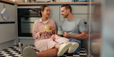 Couple sitting on the kitchenfloor drinking coffee and talking