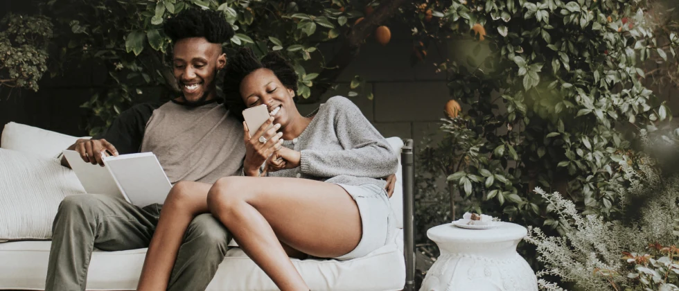 A couple sitting on a bench in the garden laughing together.