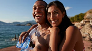 A couple smiling as they stand together with snorkelling equipment in their hands.