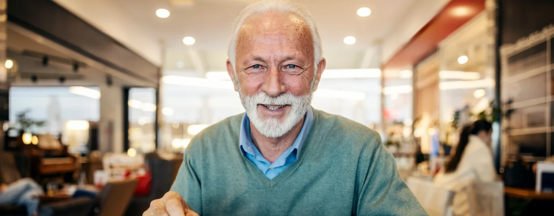 Elderly man smiling while having coffee in a café